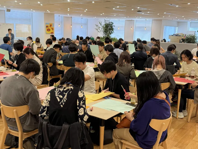 キーノートで会場いっぱいの参加者が色画用紙を使って工作している様子